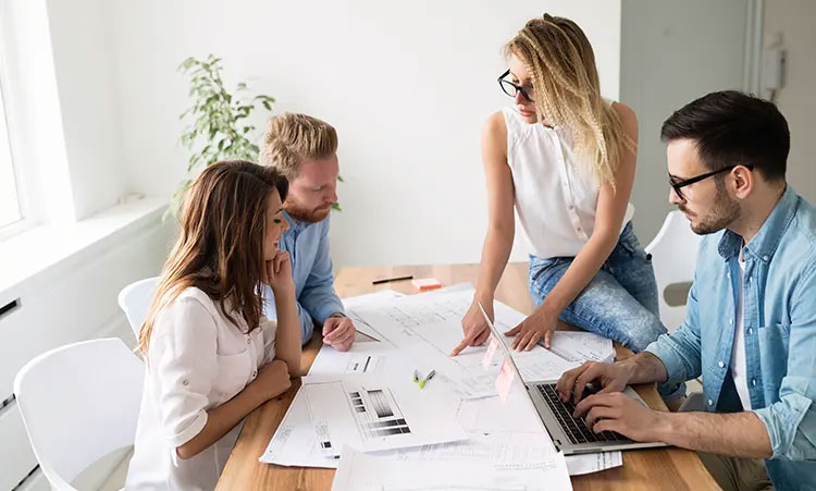 A small group gathered around a table in discussion, conveying collaboration, community, and shared growth.